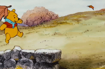 A GIF of Winnie the Pooh playing with falling leaves.